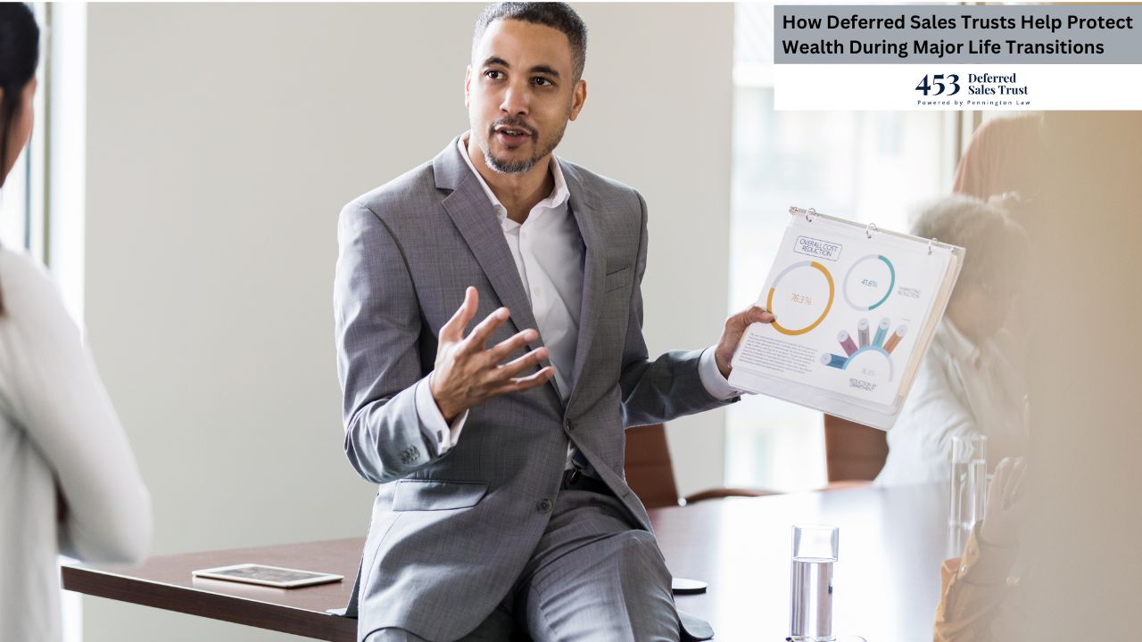 A businessman is presenting financial charts to a client during a meeting. The image shows a medium-close-up shot of a dark-skinned man in a gray suit sitting on the edge of a table, gesturing animatedly with his hands as he holds up a financial report featuring pie charts and bar graphs.