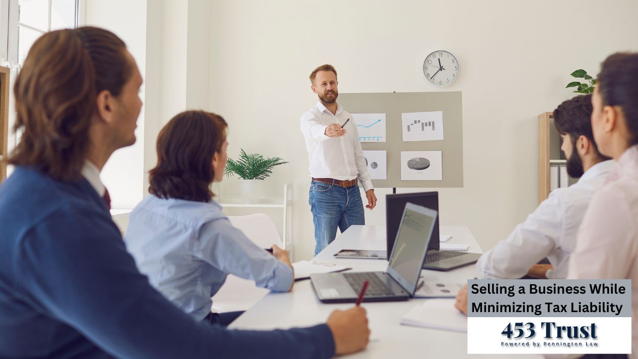 A man, centrally positioned, is standing and presenting to the group. He is light-skinned and wearing a light-colored collared shirt and light-colored jeans. He is holding a pen or pointer.