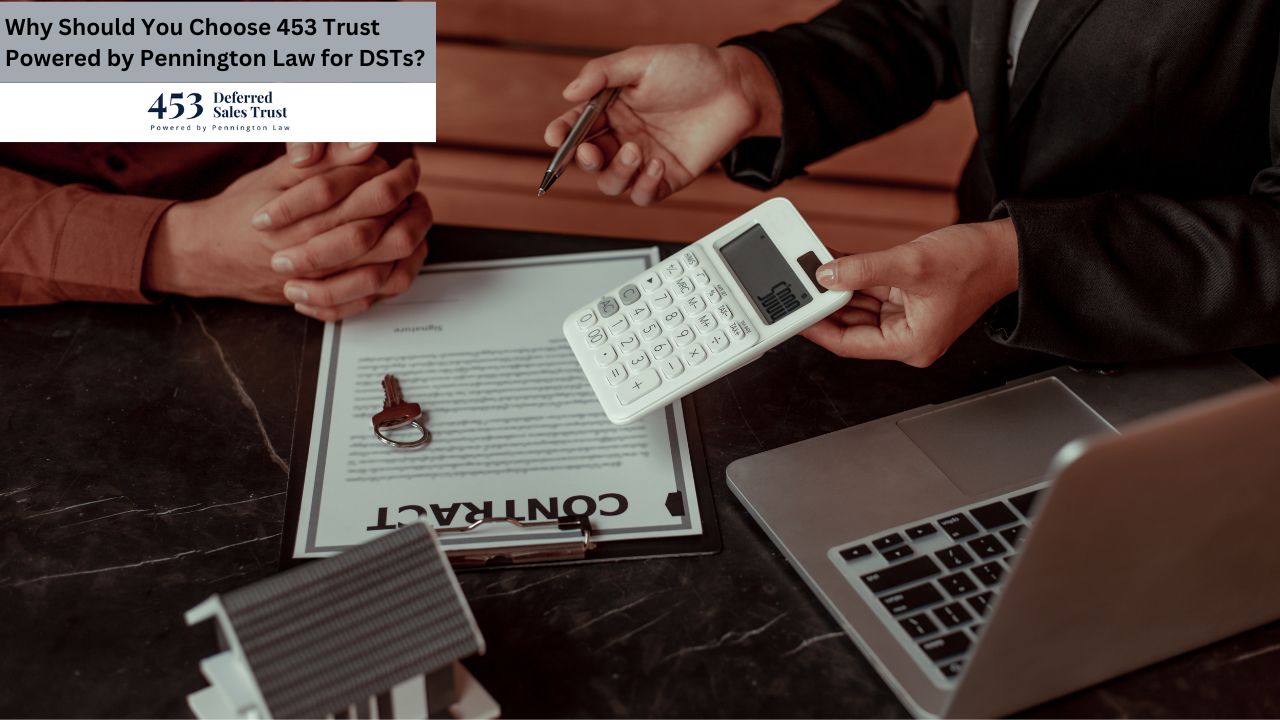 A real estate transaction is being finalized, with two individuals reviewing documents, a calculator, and a house key on a dark table.